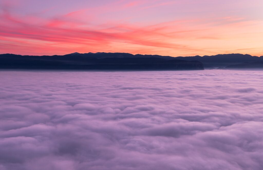 red sky over mountains above the fluffy purple clouds